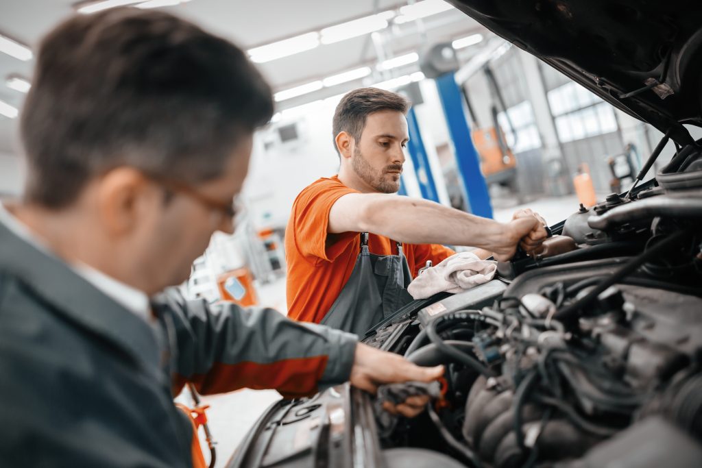 Two men working on a car engine in an auto repair shop.